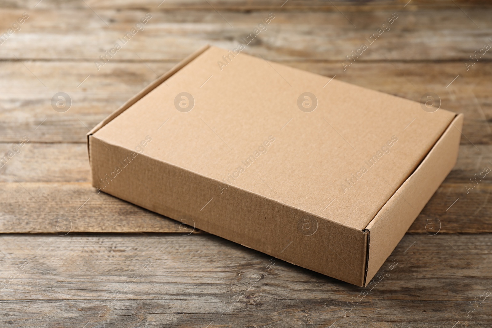 Photo of One closed cardboard box on wooden table