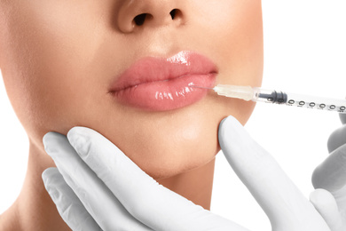 Young woman getting lips injection on white background, closeup