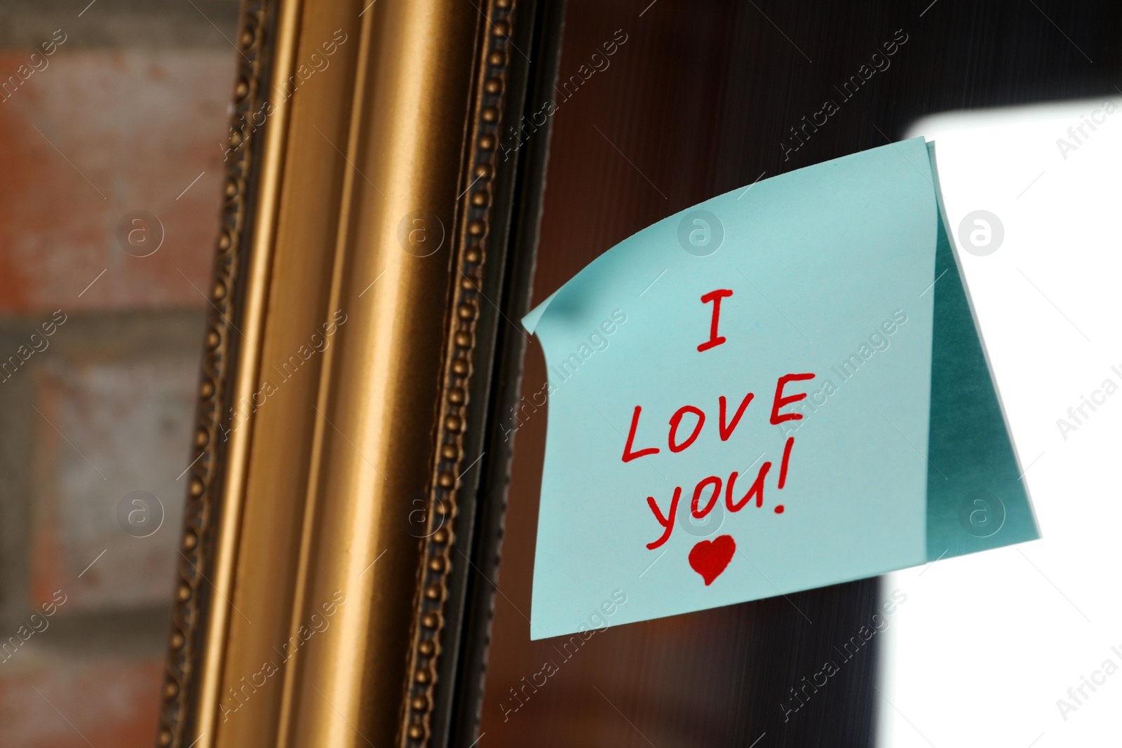 Photo of Note with phrase I Love You attached to mirror