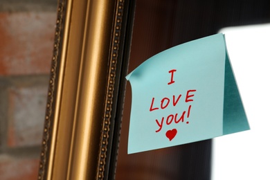 Note with phrase I Love You attached to mirror