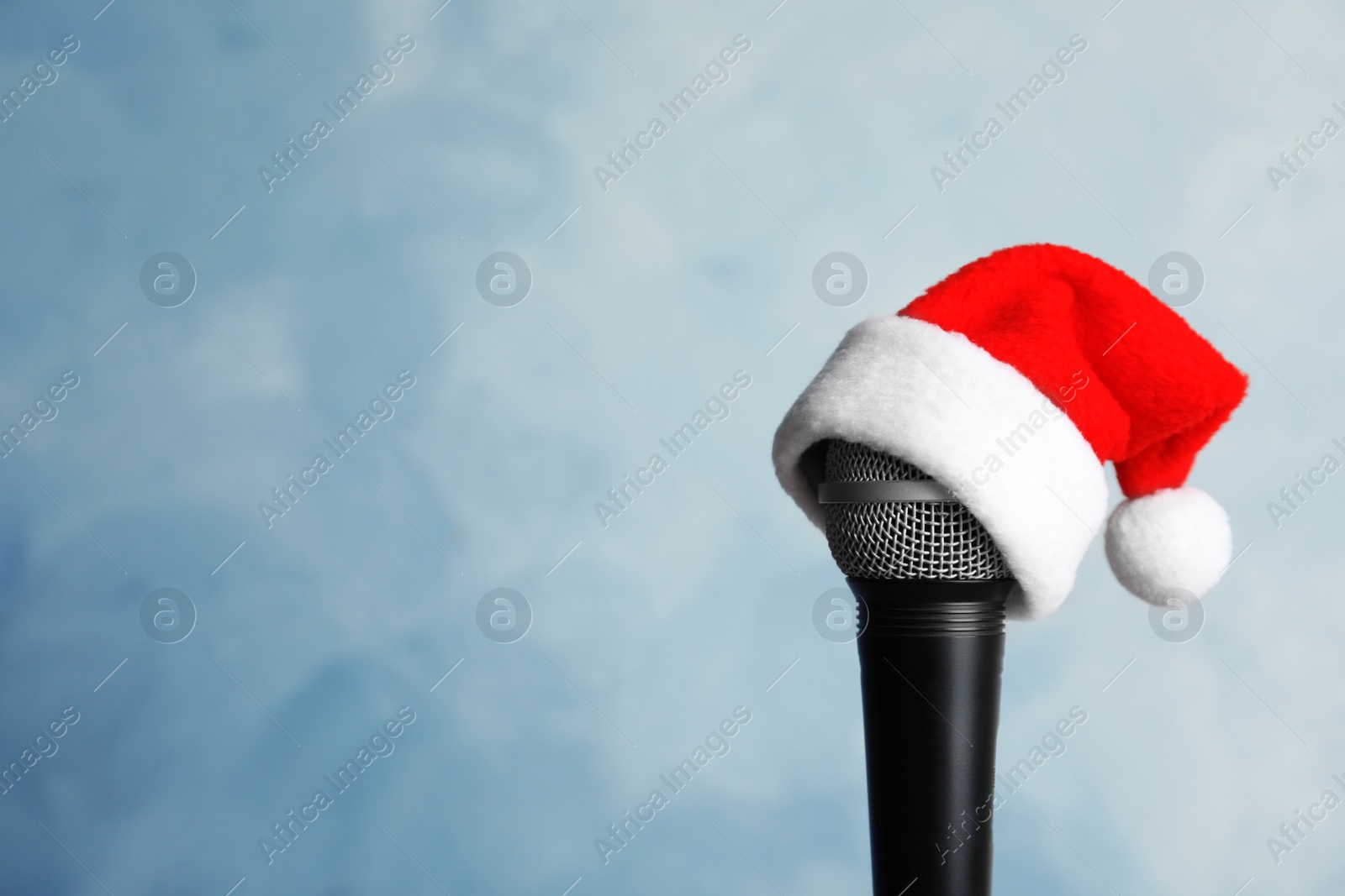 Photo of Microphone with Santa hat on color background. Christmas music concept