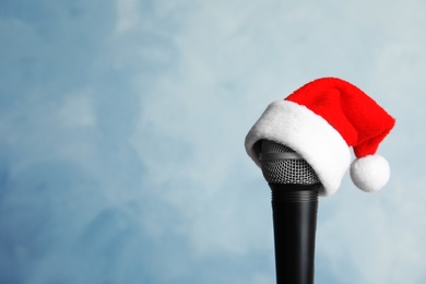 Photo of Microphone with Santa hat on color background. Christmas music concept