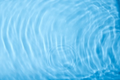 Photo of Concentric waves on blue water surface after falling drops, top view