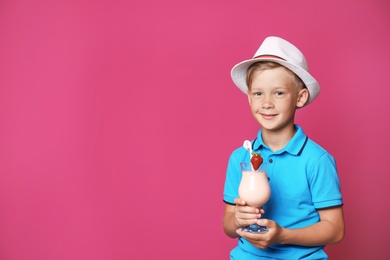 Photo of Little boy with glass of milk shake on color background