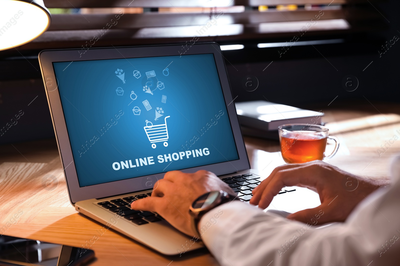 Image of Man using laptop for online shopping at wooden table, closeup