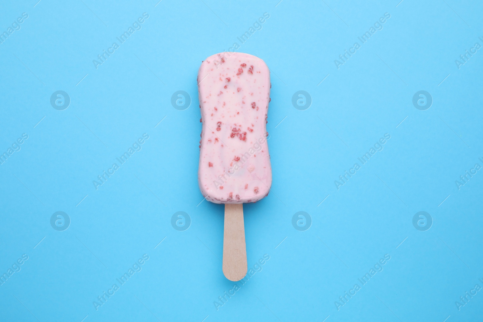 Photo of Delicious glazed ice cream bar on light blue background, top view