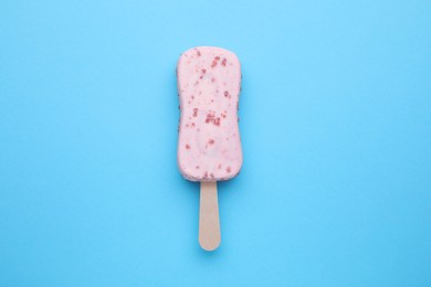 Photo of Delicious glazed ice cream bar on light blue background, top view