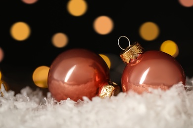 Beautiful Christmas balls on snow against blurred festive lights