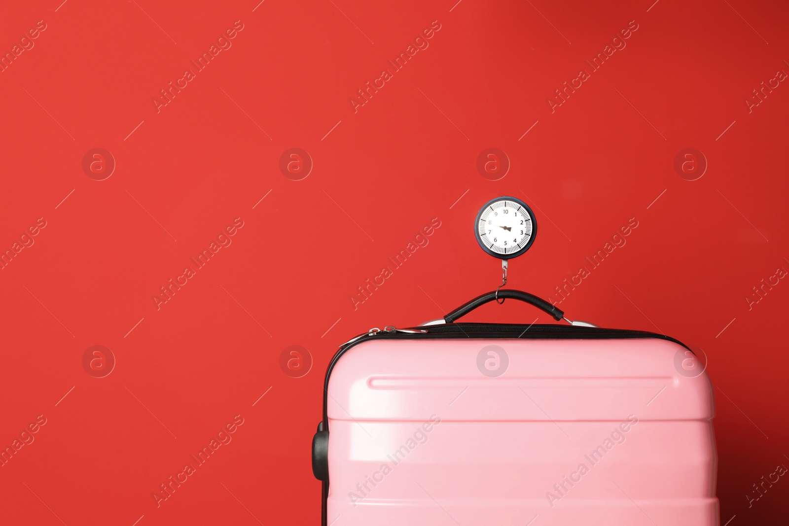 Photo of Modern suitcase and hanging scales against color background, space for text