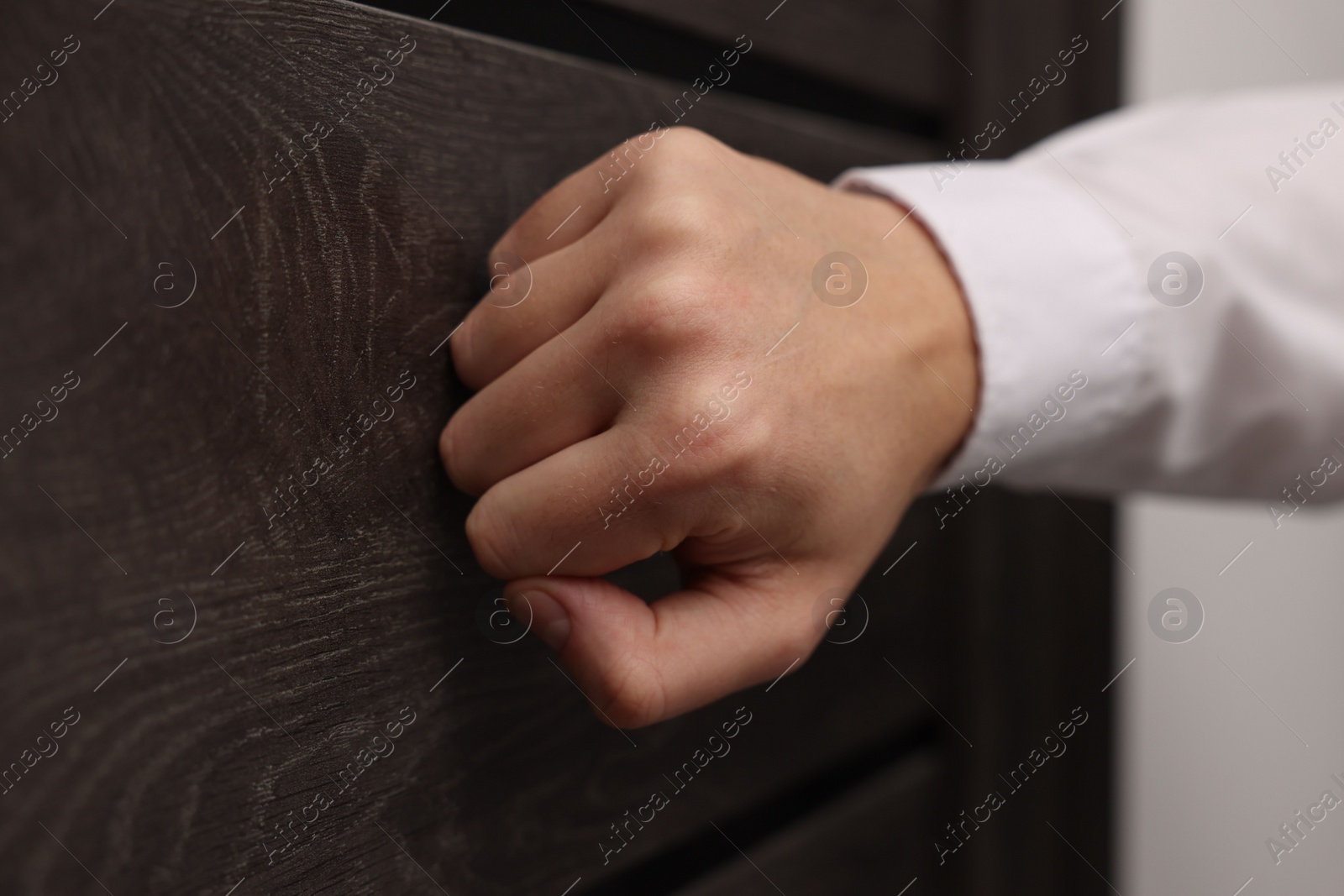 Photo of Collector knocking on door indoors, closeup view