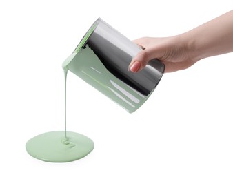 Photo of Woman pouring light green paint from can on white background, closeup