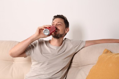 Photo of Handsome man drinking beverage on sofa indoors