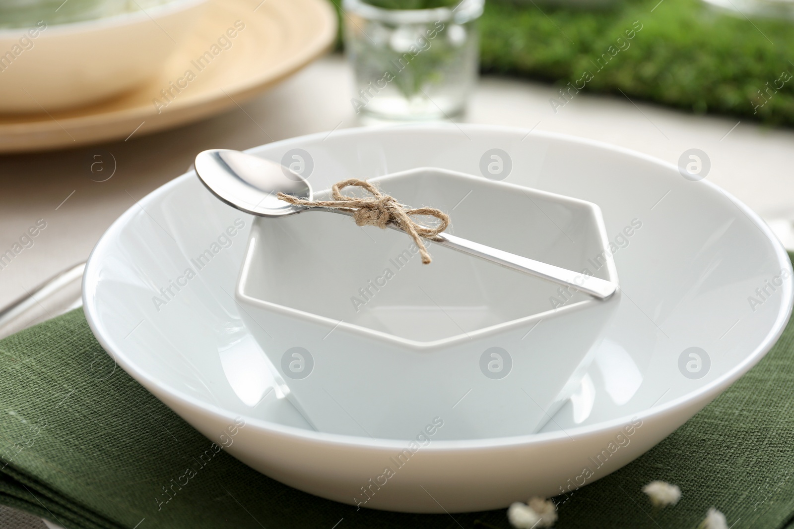 Photo of White dishes with spoon on table, closeup. Festive setting