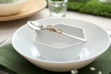 Photo of White dishes with spoon on table, closeup. Festive setting