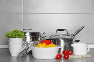 Photo of Different cookware and fresh vegetables on grey countertop