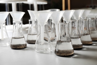 Photo of Laboratory glassware with soil extracts and funnels on table