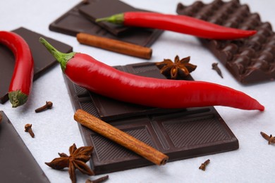 Delicious chocolate, fresh red chili peppers and spices on white table, closeup