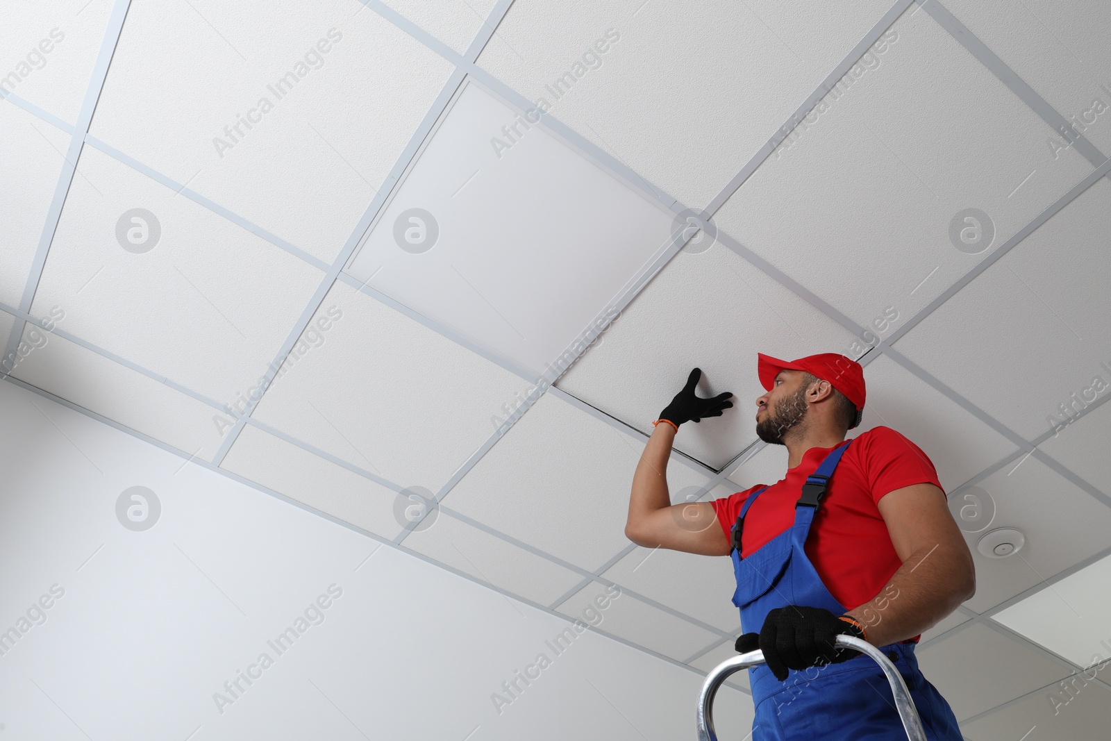 Photo of Electrician repairing ceiling light indoors, low angle view. Space for text