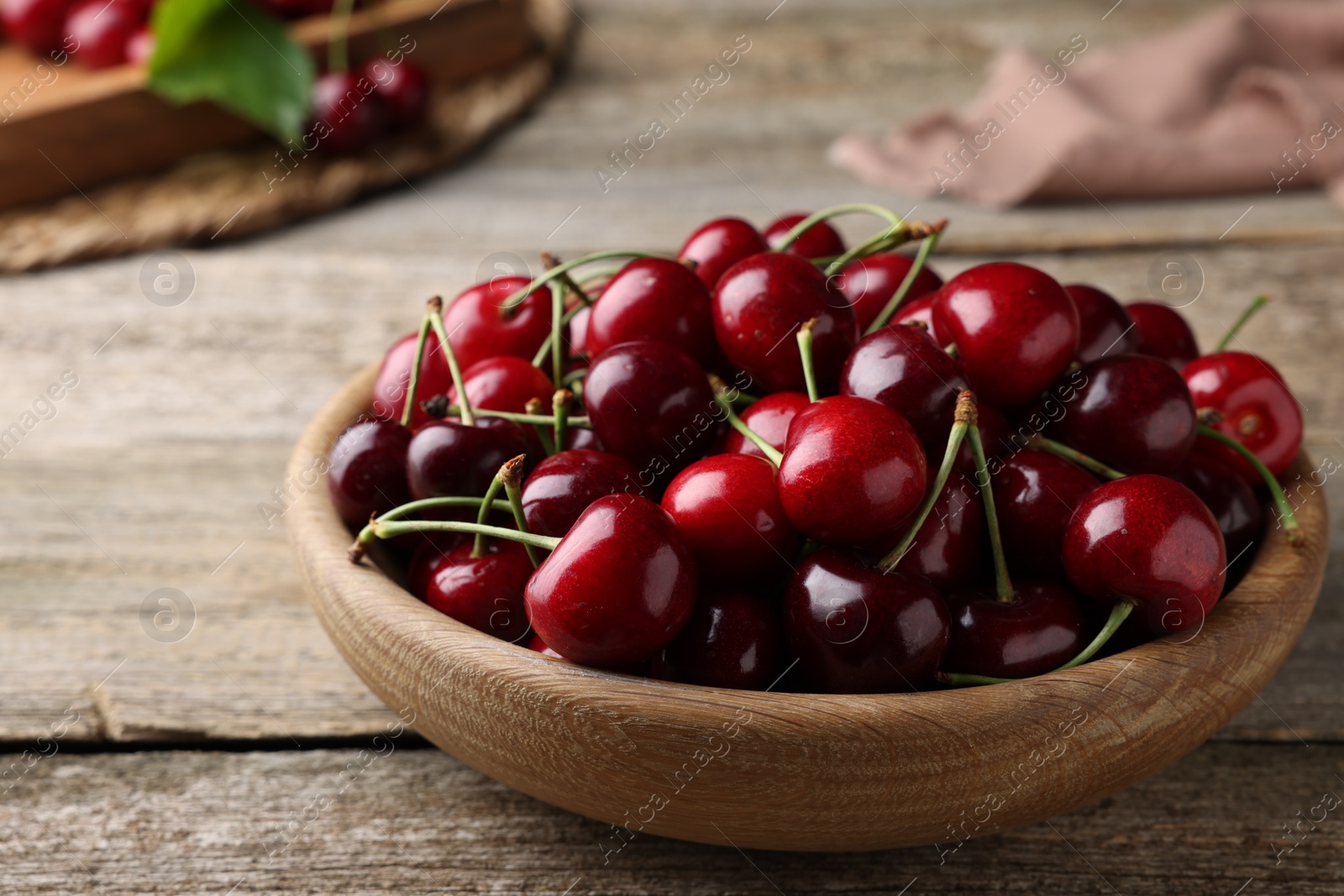 Photo of Fresh ripe cherries in bowl on wooden table, closeup