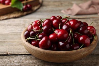 Fresh ripe cherries in bowl on wooden table, closeup