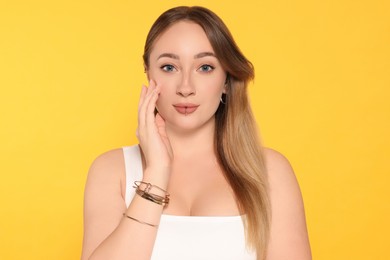 Photo of Young woman with lip and ear piercings on yellow background