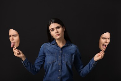 Woman holding masks with her face showing different emotions on black background. Balanced personality