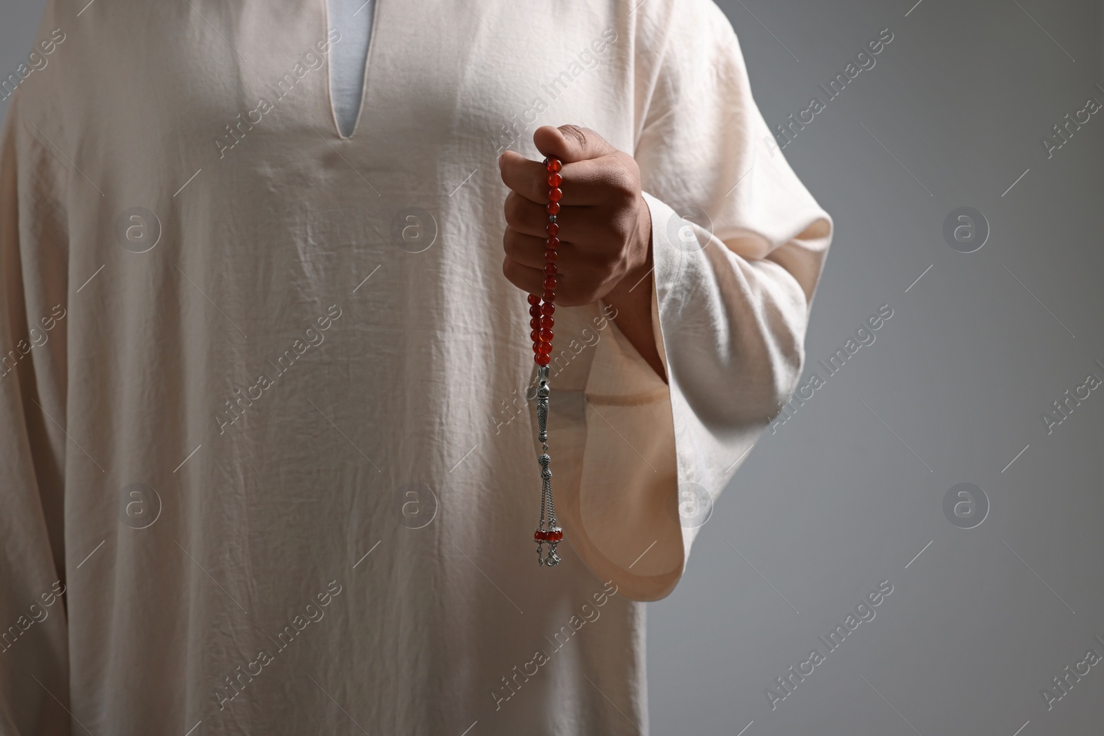 Photo of Muslim man with misbaha on light grey background, closeup