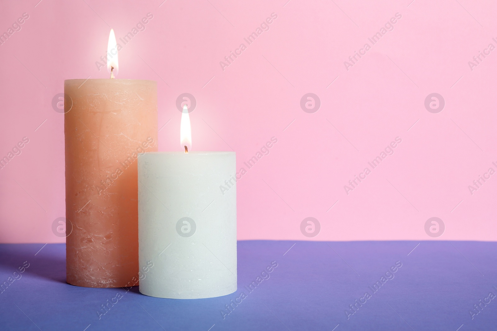 Photo of Decorative wax candles on table against color background