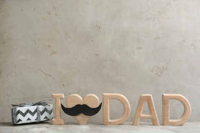 Photo of Gift box and phrase I LOVE DAD on light grey stone background, space for text. Happy Father's day