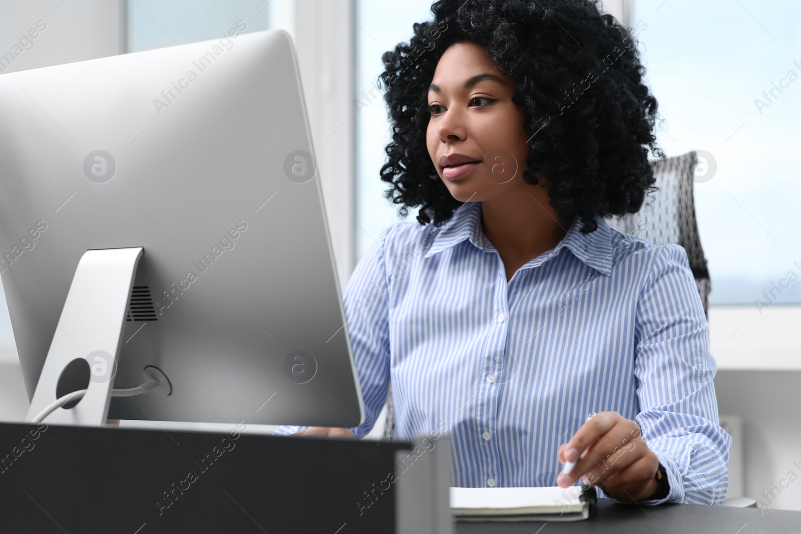 Photo of Young woman working on computer at table in office