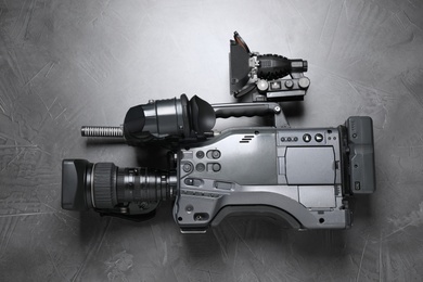 Photo of Modern video camera with flashlight on grey stone background, top view