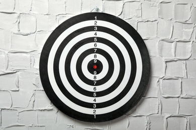 Photo of Dart board hanging on white textured wall