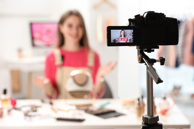 Photo of Beauty blogger filming make up tutorial at home, focus on camera