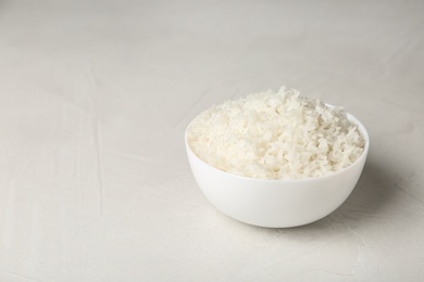 Photo of Bowl of boiled rice on light background. Space for text