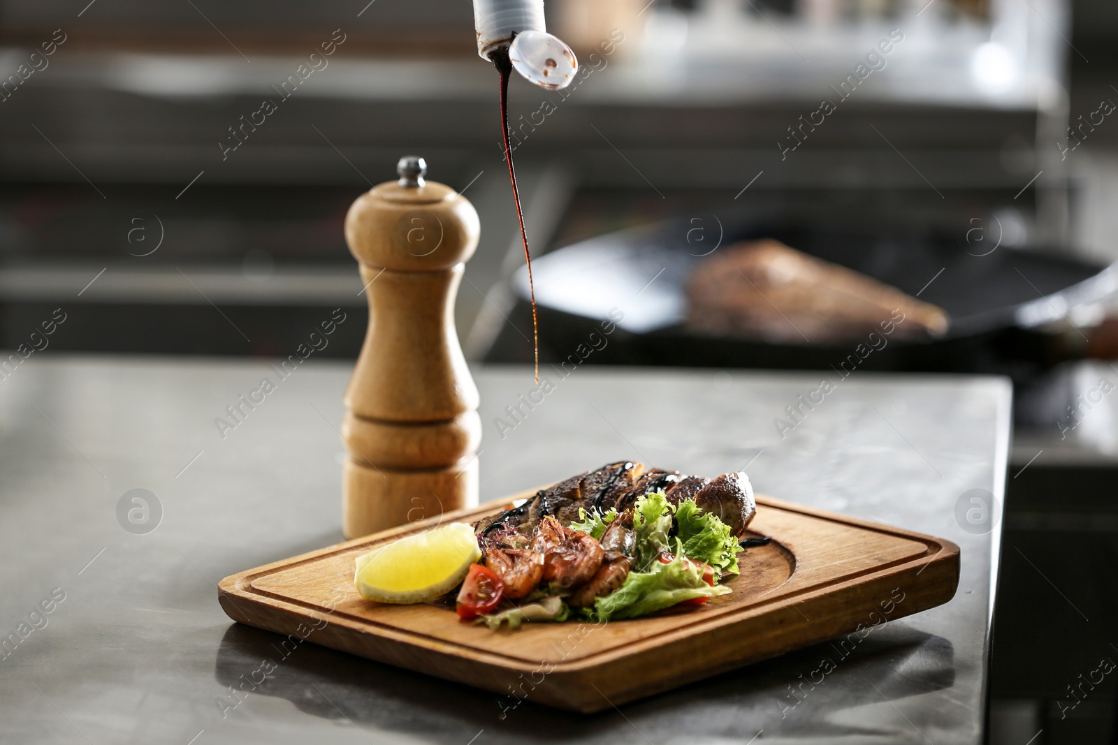 Photo of Adding sauce to tasty meal on table in restaurant kitchen. Cooking food