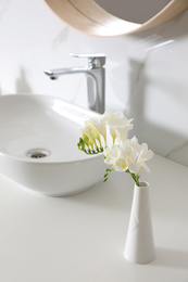 Photo of Beautiful bouquet with white freesia flowers in bathroom