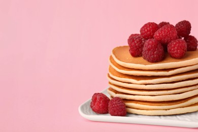 Photo of Stack of tasty pancakes with raspberries on pink background, closeup. Space for text