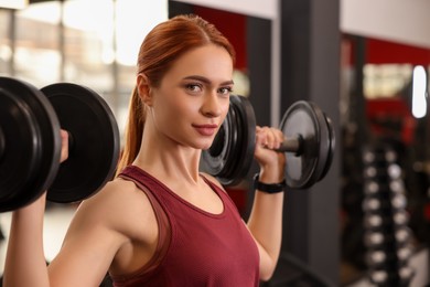 Athletic young woman with barbell training in gym