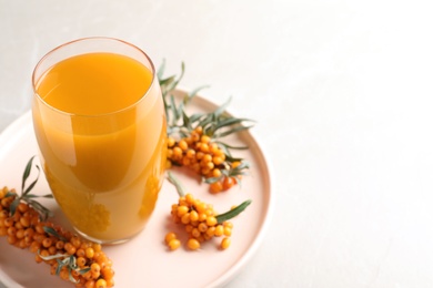 Photo of Delicious sea buckthorn juice and fresh berries on light grey marble table, closeup. Space for text