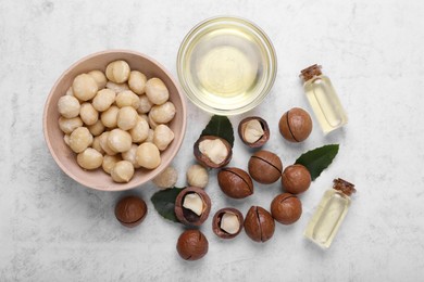 Photo of Delicious organic Macadamia nuts and cosmetic oil on light gray table, flat lay