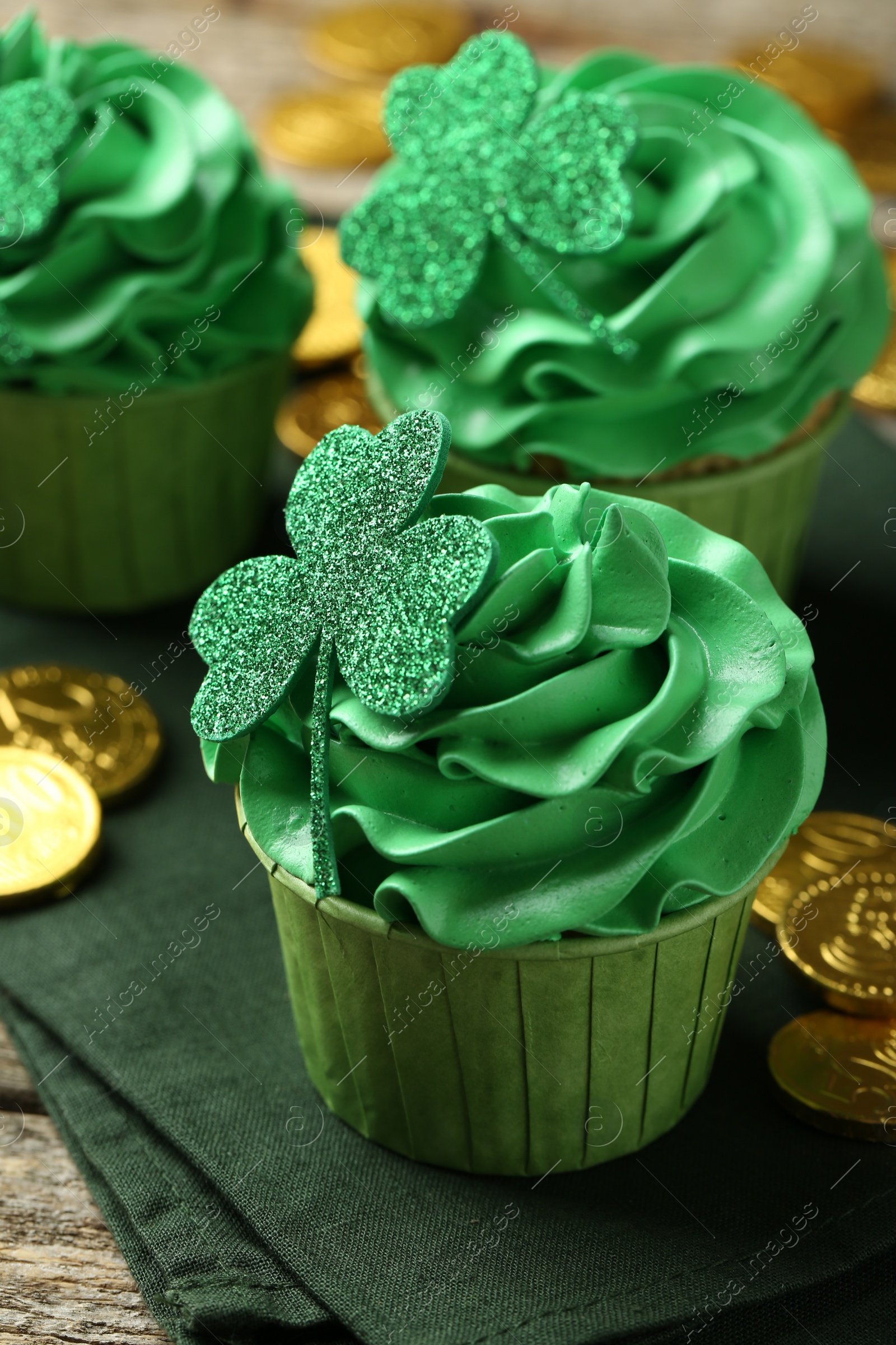 Photo of St. Patrick's day party. Tasty cupcakes with clover leaf toppers and green cream on wooden table, closeup