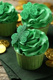 St. Patrick's day party. Tasty cupcakes with clover leaf toppers and green cream on wooden table, closeup