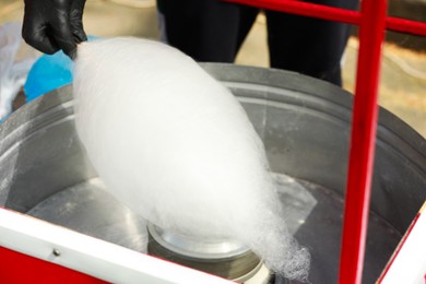 Man making cotton candy with machine outdoors, closeup