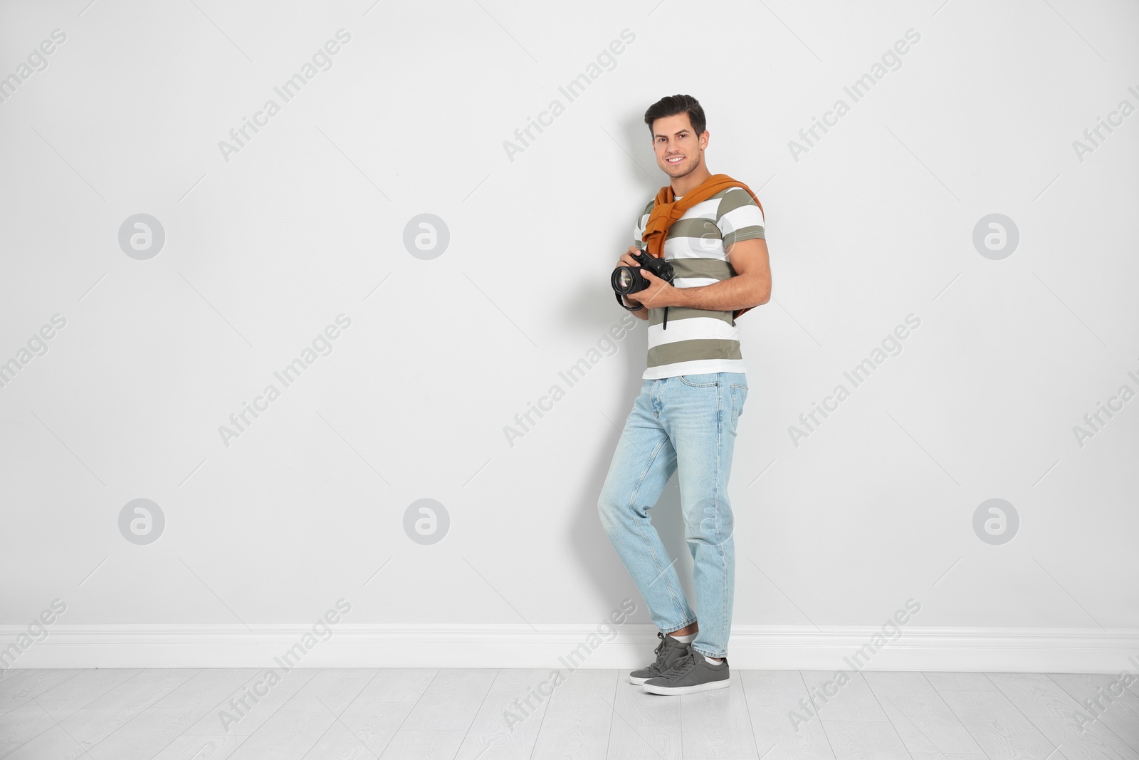 Photo of Professional photographer working near white wall in studio. Space for text