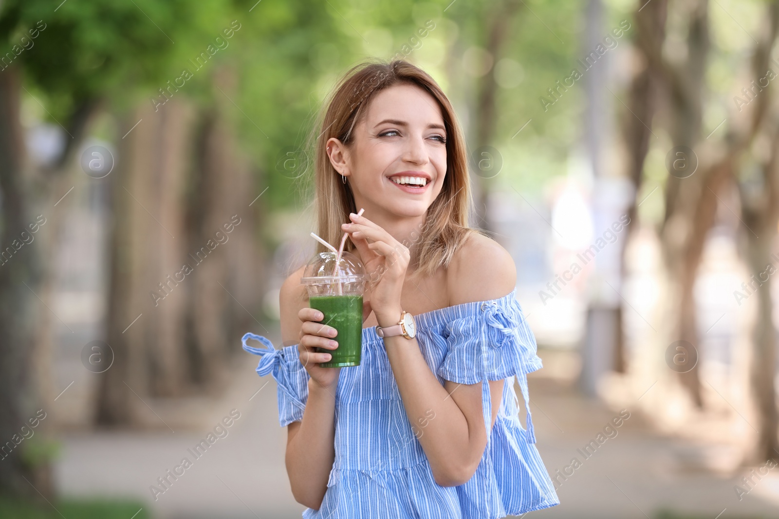 Photo of Young woman with plastic cup of healthy smoothie outdoors