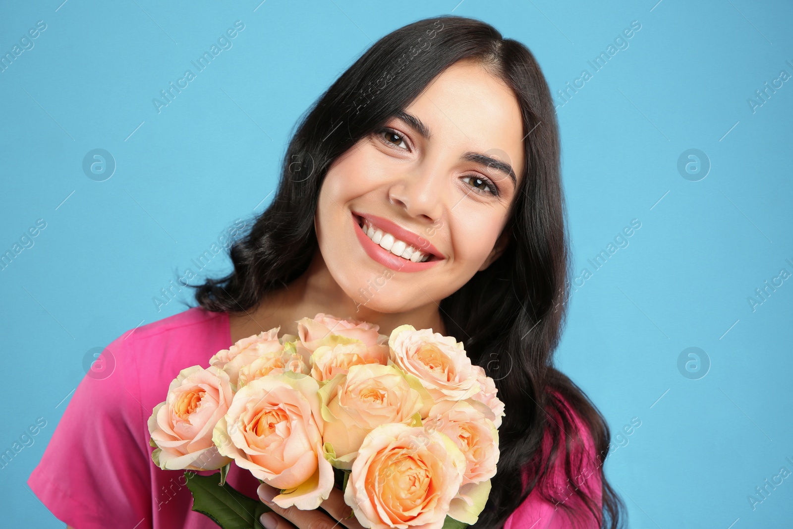 Photo of Portrait of smiling woman with beautiful bouquet on light blue background