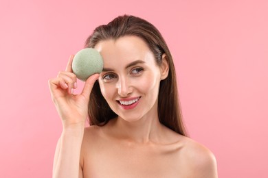 Photo of Happy young woman with face sponge on pink background