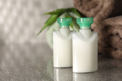 Photo of Mini bottles of cosmetic products on grey textured table, space for text