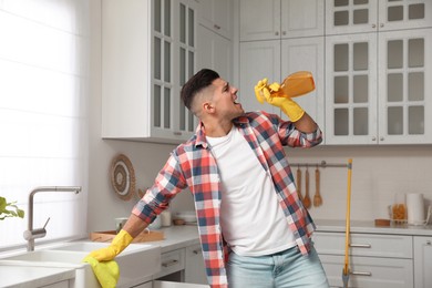 Man with spray bottle and rag singing while cleaning at home