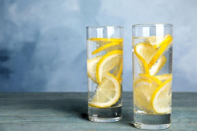 Photo of Soda water with lemon slices on blue wooden table. Space for text